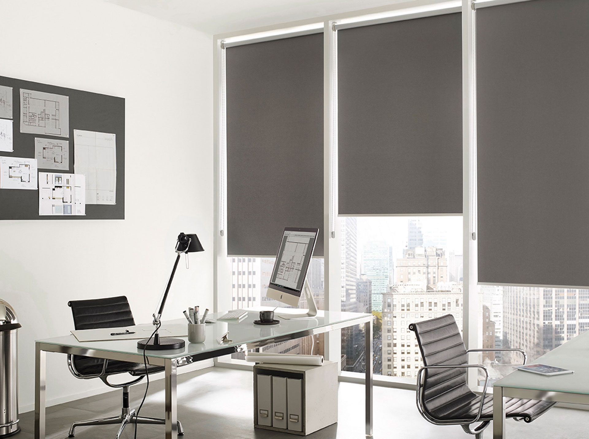 KADECO Rollo als Sichtschutz, Sonnenschutz und Blendschutz mit abdunkelndem Stoff in grau im stilvollen Büro. KADECO Rollo im stilvollen Büro als Sichtschutz, Sonnenschutz und Blendschutz für PC-Arbeitsplätze in einem klassischem Grau mit abdunkelndem St